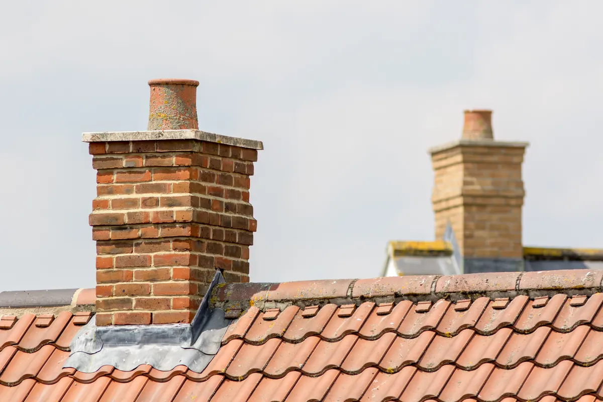 Two brick chimney stacks above a tiled roof