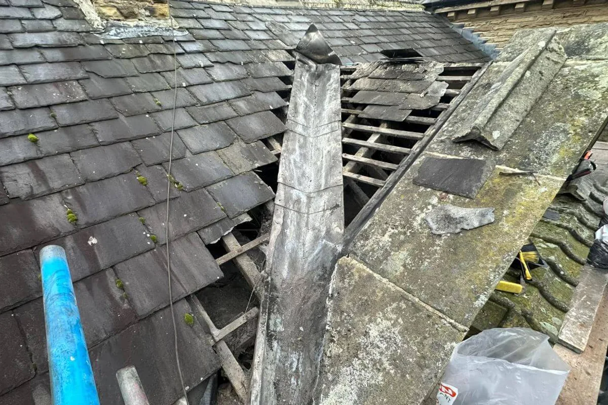 A slate roof opened up to the battens, with scaffold alongside