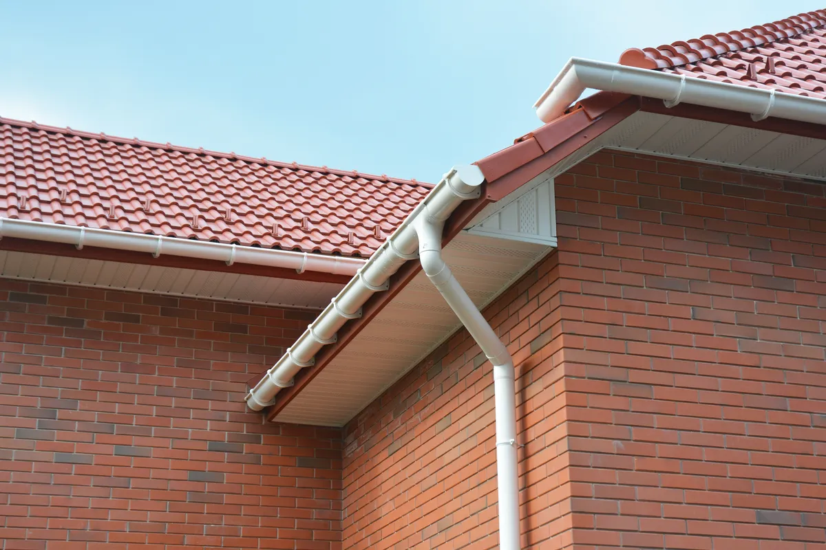 A white fascia, soffit and downpipe on a brick house