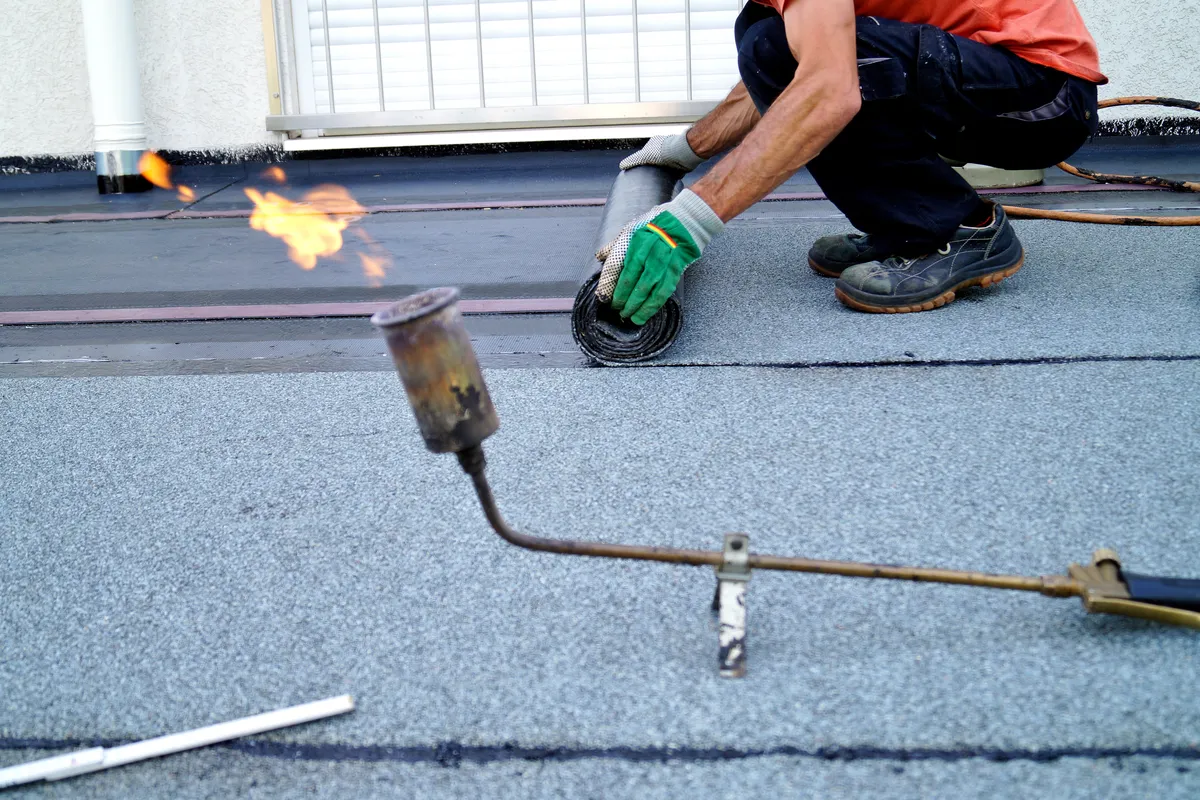 A flat roof membrane being torched down along a joint