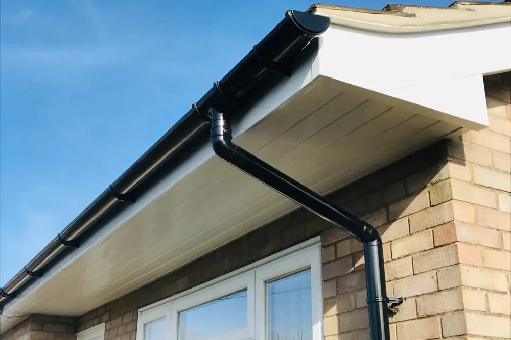 New black guttering and a downpipe on a finished soffit run