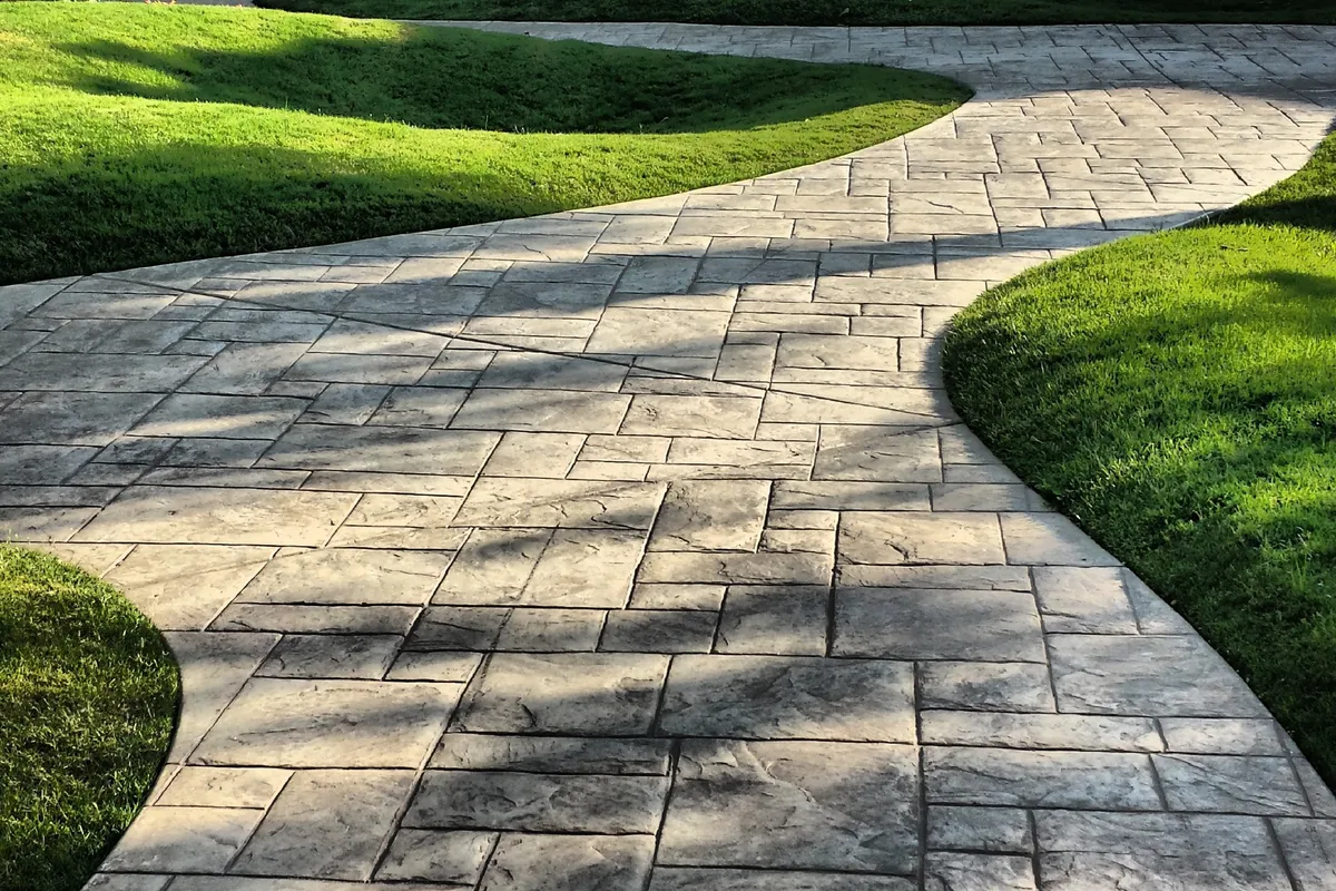 A block paved path curving around a lawn