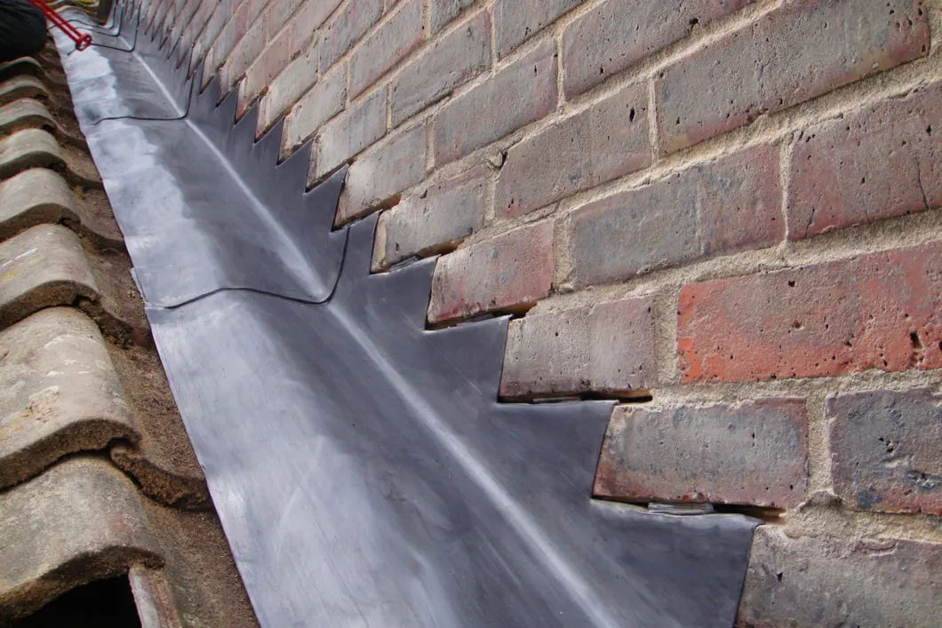Lead soakers and a stepped flashing dressed into a brick abutment wall
