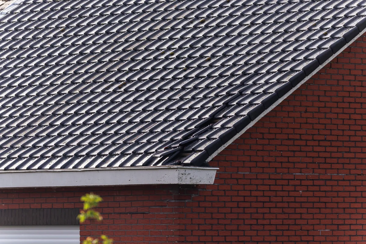 A finished concrete tiled roof over red brickwork