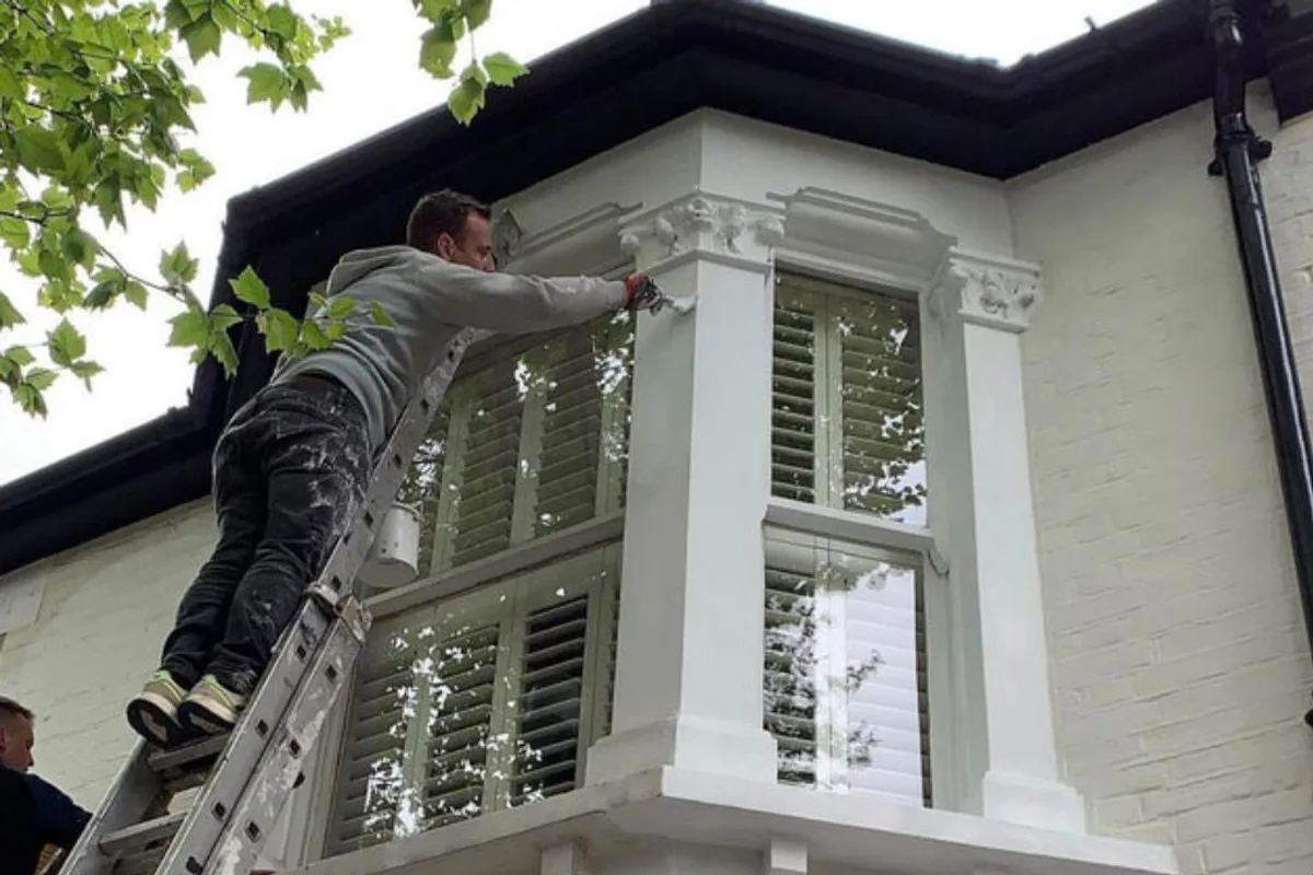 Exterior painting in progress on a freshly rendered bay window