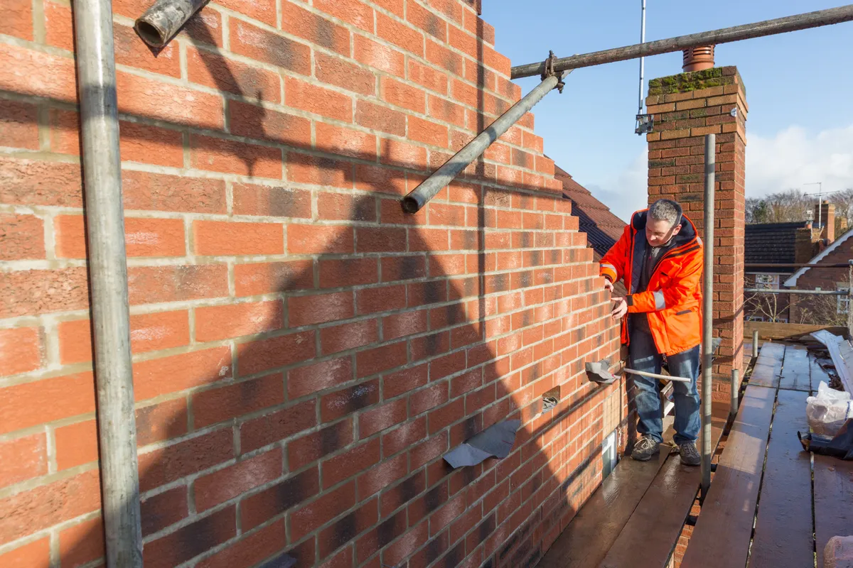 Repointing being carried out on a brick wall from a scaffold