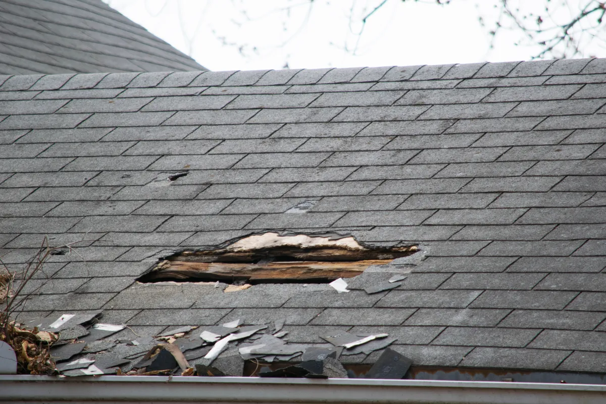 A hole in a slate roof with the broken slates below it