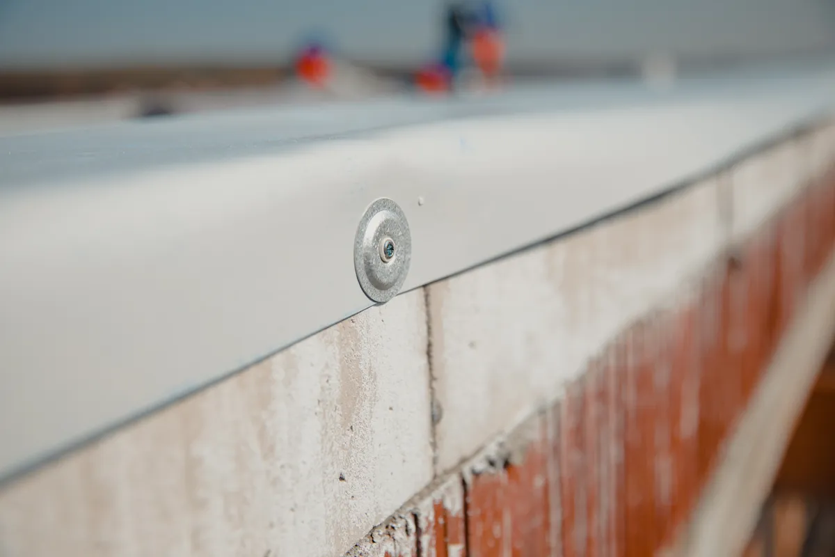 An EPDM termination bar fixed along a wall upstand