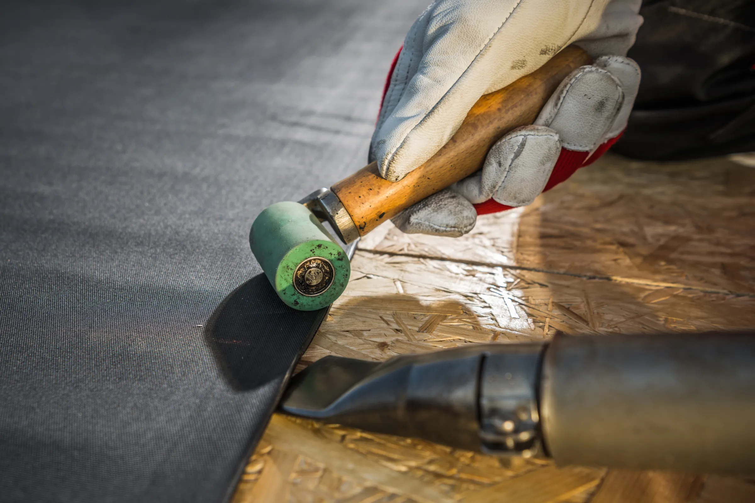 An EPDM rubber membrane being dressed down onto a new flat roof deck