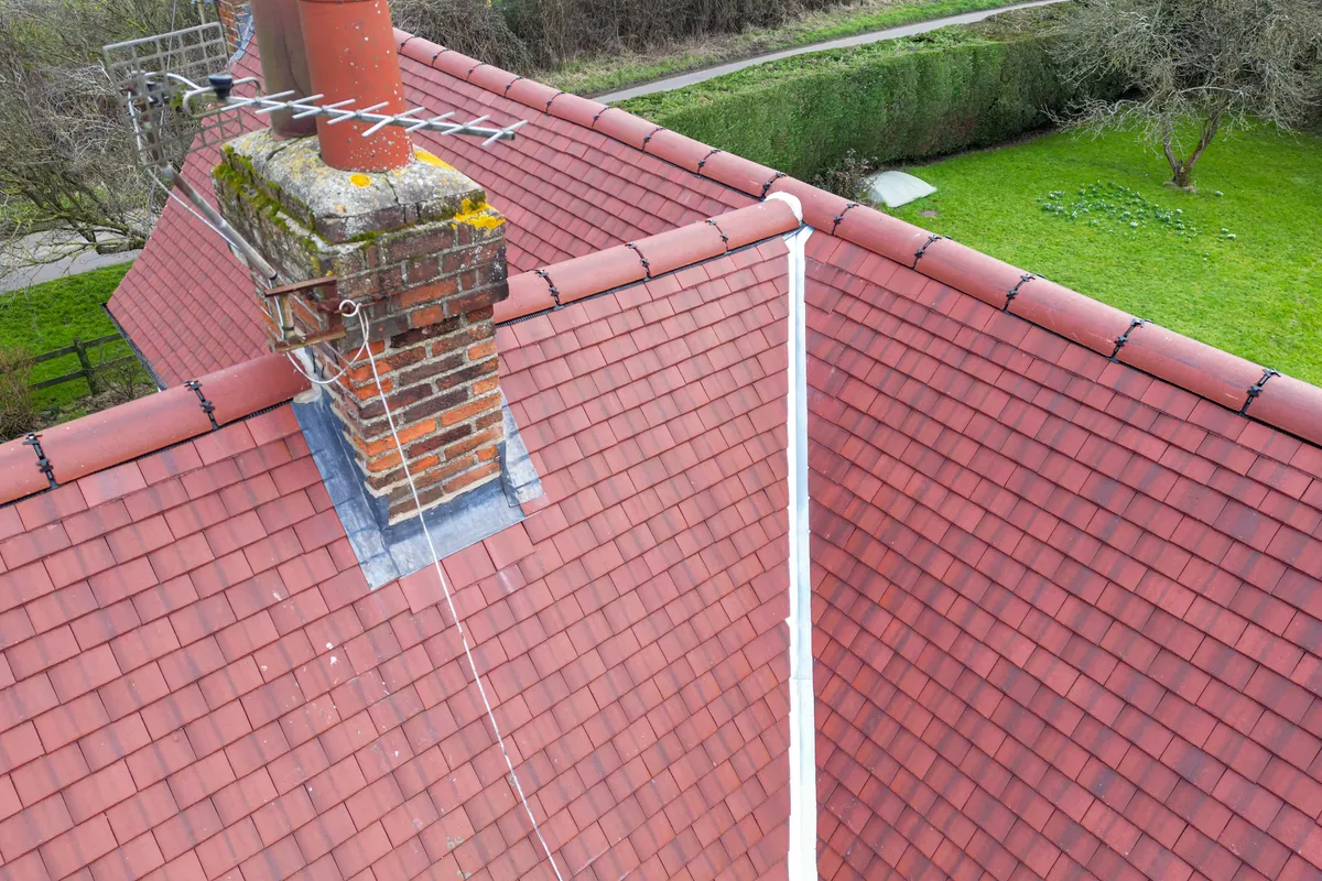A red clay tiled roof and chimney over a garden