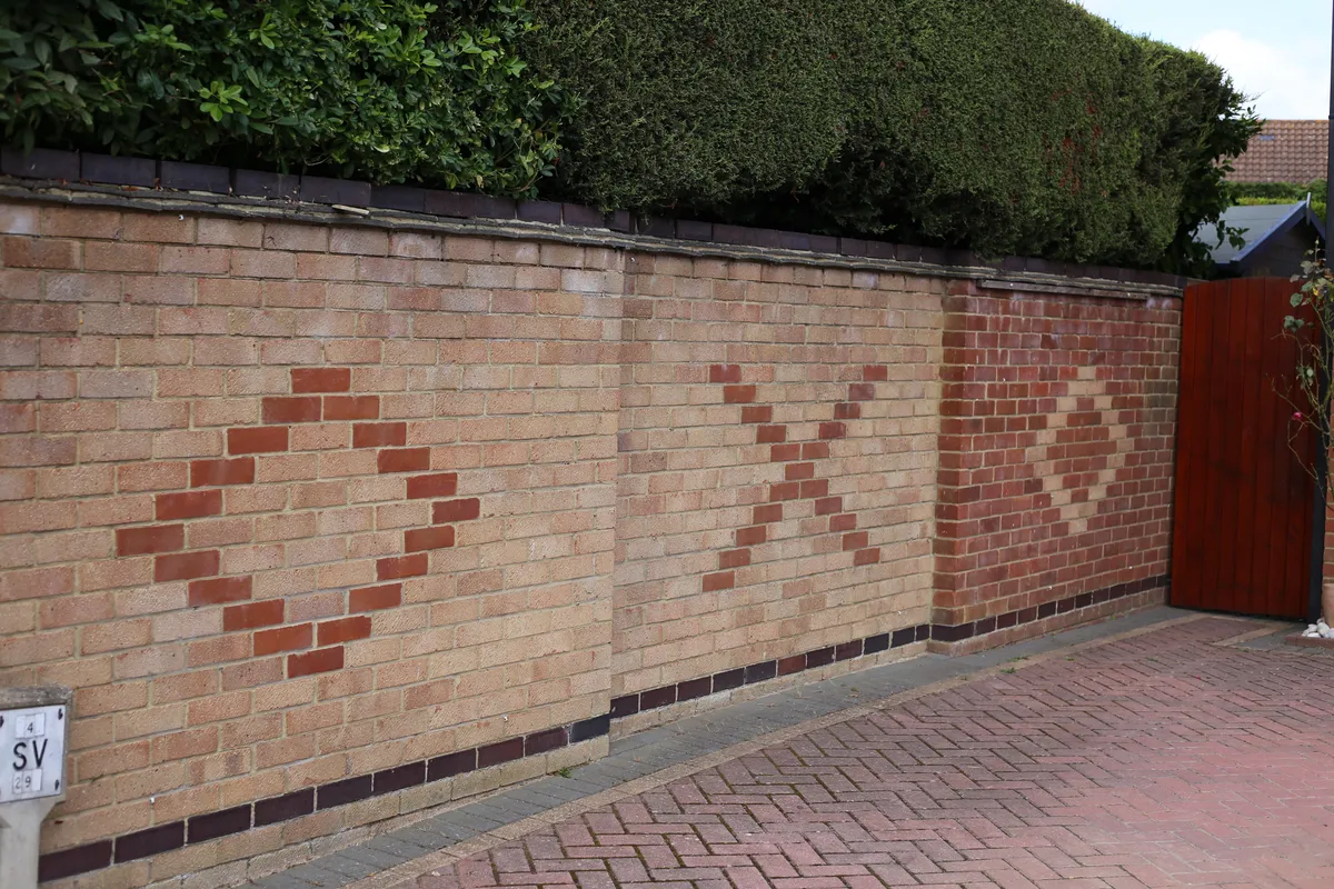 A brick front wall with piers along a pavement